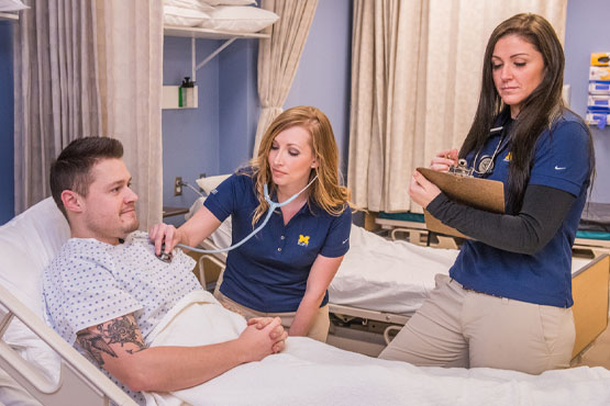 Two students working with individual in respiratory therapy class.