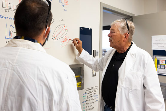 Student listening to faculty member in a biology lab at the University of Michigan-Flint.