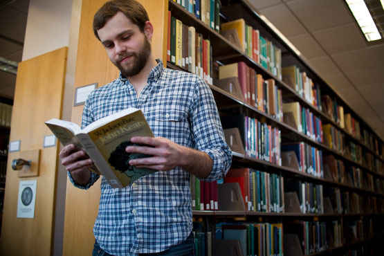 Estudiante leyendo un libro en la biblioteca.