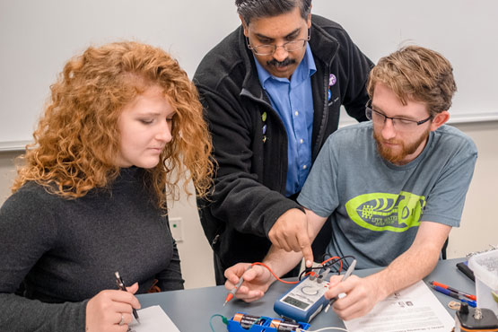 Professor working with two students in a physics class.
