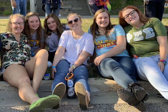 Members from CPA sitting on the curb together for a fun picture
