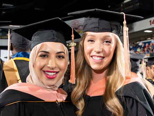 Two graduates at the University of Michigan-Flint Commencement Ceremony.