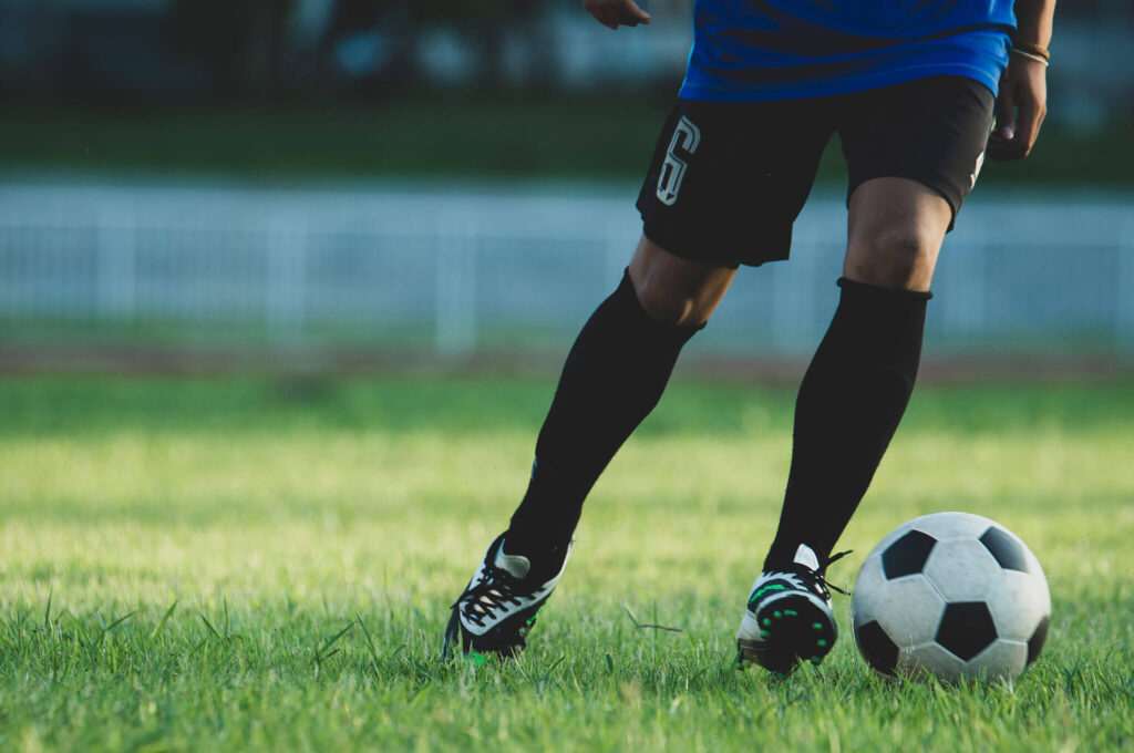 Individual kicking around a soccer ball outside.